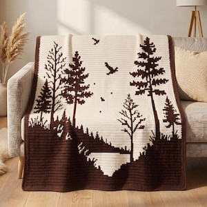 May include: A rectangular crochet blanket featuring a two-tone forest landscape design. The pattern displays dark brown pine trees, a ground line, and flying birds against a cream-colored background, finished with a solid dark brown border.