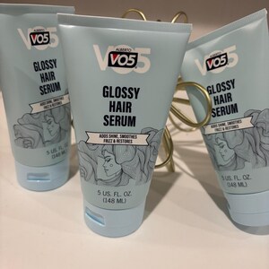 May include: Several tubes of VO5 Glossy Hair Serum are displayed. The light blue tubes have white text that reads "Glossy Hair Serum" and "Adds Shine, Smooths Frizz & Restores." Each tube contains 5 US fl. oz. (148 mL) of product.
