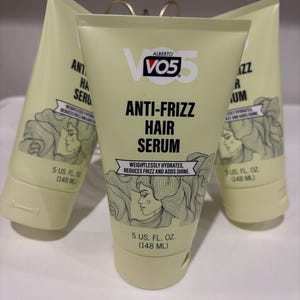 May include: Three tubes of Alberto VO5 Anti-Frizz Hair Serum. The tubes are light yellow with black text and a drawing of a woman with flowing hair. Each tube contains 148 ml of serum. The text states the serum weightlessly hydrates, reduces frizz, and adds shine.