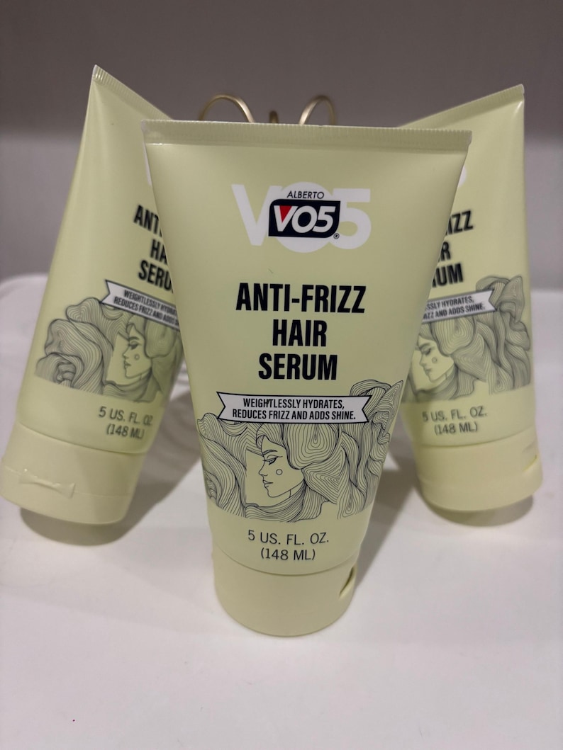 May include: Three tubes of Alberto VO5 Anti-Frizz Hair Serum. The tubes are light yellow with black text and a drawing of a woman with flowing hair. Each tube contains 148 ml of serum. The text states the serum weightlessly hydrates, reduces frizz, and adds shine.