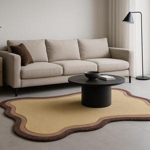 May include: A modern living room setup featuring a beige sofa, a black coffee table, and a unique, free-form rug in shades of yellow and brown. A black floor lamp and wooden cabinet complete the contemporary design.