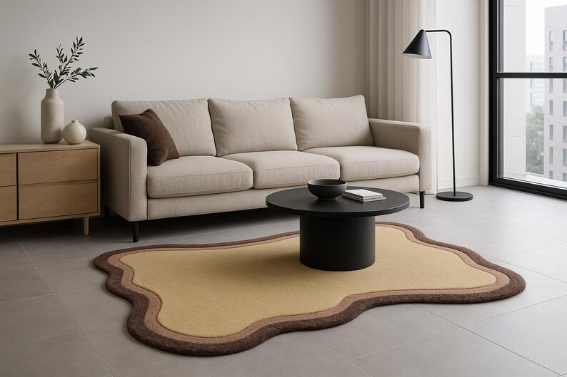May include: A modern living room setup featuring a beige sofa, a black coffee table, and a unique, free-form rug in shades of yellow and brown. A black floor lamp and wooden cabinet complete the contemporary design.