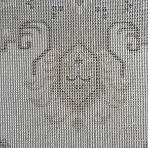 May include: A woven textile featuring a repeating pattern of dark gray and light beige geometric shapes. The design includes a central diamond motif surrounded by symmetrical scrollwork and floral-inspired elements on a textured fabric surface.