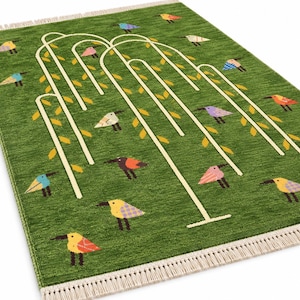 May include: A rectangular green area rug featuring a stylized white willow tree design with yellow leaves. The rug is decorated with numerous small, multi-colored birds in shades of blue, pink, orange, purple, and yellow. It has white fringe.