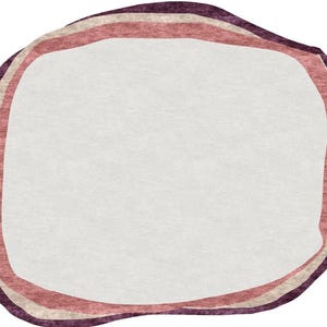 May include: A rug with an organic shape and a white center. The border features three bands of color: a dark purple outer edge, a light beige middle band, and a reddish-pink inner band. The rug has a soft, textured appearance.