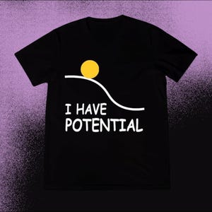 May include: Black t-shirt with a graphic design featuring a yellow circle atop a white curved line, with the words "I HAVE POTENTIAL" in white block letters below. The shirt is made of a soft material.