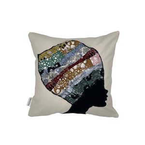 Könnte beinhalten: Quadratisches Kissen mit cremefarbenem Hintergrund. Es zeigt eine schwarze Silhouette des Profils einer Person, verziert mit einem farbenfrohen Patchwork-Design, das ein Kopftuch darstellt. Das Patchwork umfasst verschiedene Muster und Farben.