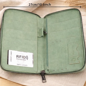May include: Open, light green wallet with multiple card slots and a zippered closure. The wallet is 10.6 inches wide and 8.66 inches tall. It features a card with "RFID PROTECTED" text. The wallet is made of a soft material and has a dark green zipper.