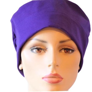 May include: A purple scrub hat made of soft, comfortable fabric. The hat is designed to be worn by medical professionals or anyone who wants a stylish and practical head covering.