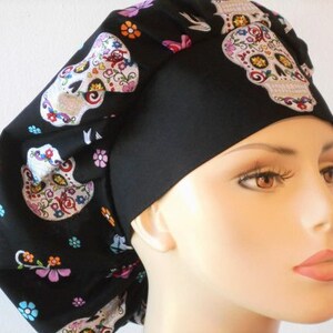 May include: Black scrub hat with a colorful sugar skull pattern. The hat has a black band and a tie at the back.