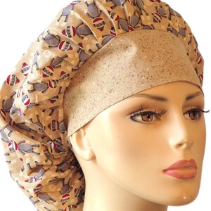 May include: A beige surgical scrub cap featuring a repeating pattern of gray sock monkey figures wearing red and white hats. The cap has a wide, speckled beige band across the forehead.