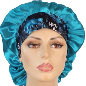 May include: A teal satin bonnet with a black and blue patterned band featuring the text "Harry Potter" and a castle design. The bonnet is designed to protect hair and maintain hairstyles.