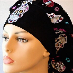 May include: Black scrub hat with a colorful sugar skull pattern. The hat has a tie at the back and is made of a soft, comfortable fabric.