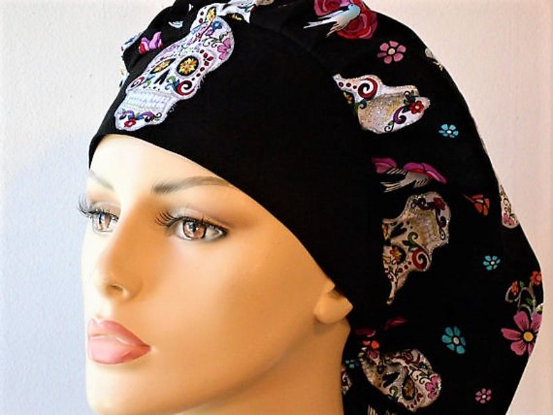 May include: Black scrub hat with a colorful sugar skull pattern. The hat has a tie at the back and is made of a soft, comfortable fabric.