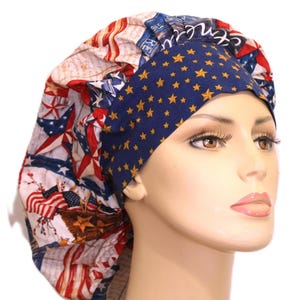 May include: A bouffant scrub cap featuring a patriotic theme with red, white, and blue colors. The fabric displays American flag motifs, stars, and script text. A wide, dark blue band with a repeating gold star pattern encircles the forehead area.