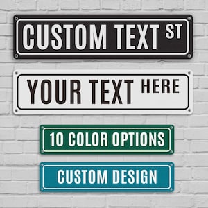 May include: Four rectangular street signs with white text on black, white, green, and teal backgrounds. The signs read "CUSTOM TEXT ST", "YOUR TEXT HERE", "10 COLOR OPTIONS", and "CUSTOM DESIGN". The signs are mounted on a white brick wall.