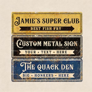Könnte beinhalten: Drei rechteckige Metallschilder mit abgenutzten Texturen. Das obere Schild ist gelb mit schwarzem Text "Jamie's Super Club" und "Best Fish Fry". Das mittlere Schild ist schwarz mit "Custom Metal Sign" und Platz für Text. Das untere Schild ist blau mit "The Quack Den".