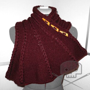 May include: A maroon knitted cowl with a cable knit pattern and wooden toggle closures.