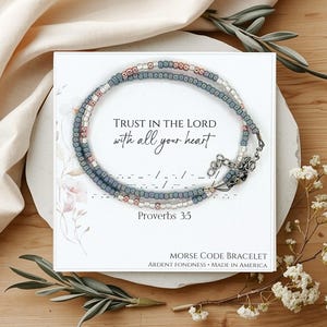 May include: A white ceramic mug with a black handle and the text "But First, Coffee" in a black, handwritten-style font. The mug is on a white surface.