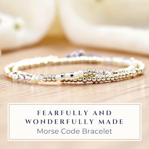 May include: A delicate, layered bracelet with gold and silver beads. The bracelet is displayed on a wooden surface with soft, blurred white fabric in the background. The text on the image reads "Fearfully and Wonderfully Made Morse Code Bracelet."