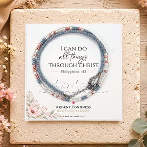 May include: A beaded bracelet featuring small blue, pink, and clear glass beads arranged in a circular pattern on a white display card. The card displays the text I CAN DO all things THROUGH CHRIST Philippians 4:13 and Morse code symbols.