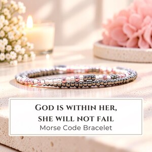 May include: A Morse code bracelet featuring a sequence of metallic rose gold, silver, and dark gray beads. The text "GOD IS WITHIN HER, SHE WILL NOT FAIL Morse Code Bracelet" is displayed in a white rectangular box below the jewelry piece.