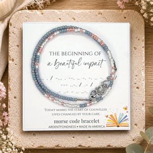 May include: A beaded bracelet with blue, pink, and clear glass beads on a white display card. The card features the text THE BEGINNING OF A beautiful impact, Morse code dots and dashes, and the words morse code bracelet and ARDENTFONDNESS.