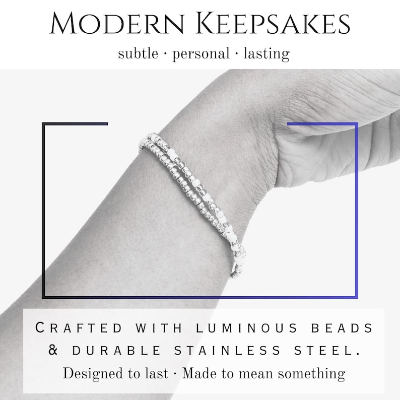 Peut inclure: Un bracelet argent&eacute; avec des perles lumineuses et de l'acier inoxydable. L'image comprend le texte "MODERN KEEPSAKES" et "CRAFTED WITH LUMINOUS BEADS & DURABLE STAINLESS STEEL. Designed to last - Made to mean something."