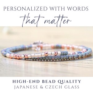 K&ouml;nnte beinhalten: Ein Perlenarmband mit einer Mischung aus metallisch ros&eacute;goldenen, irisierend blauen und silbernen Glasperlen. Der Text oben lautet PERSONALIZED WITH WORDS That matter und der Text unten lautet HIGH-END BEAD QUALITY JAPANESE & CZECH GLASS.