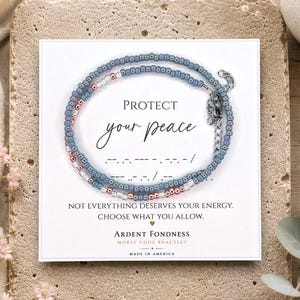 May include: A beaded bracelet with blue, clear, and metallic beads on a white display card. The card features the text PROTECT your peace, Morse code symbols, and the phrase NOT EVERYTHING DESERVES YOUR ENERGY. CHOOSE WHAT YOU ALLOW.