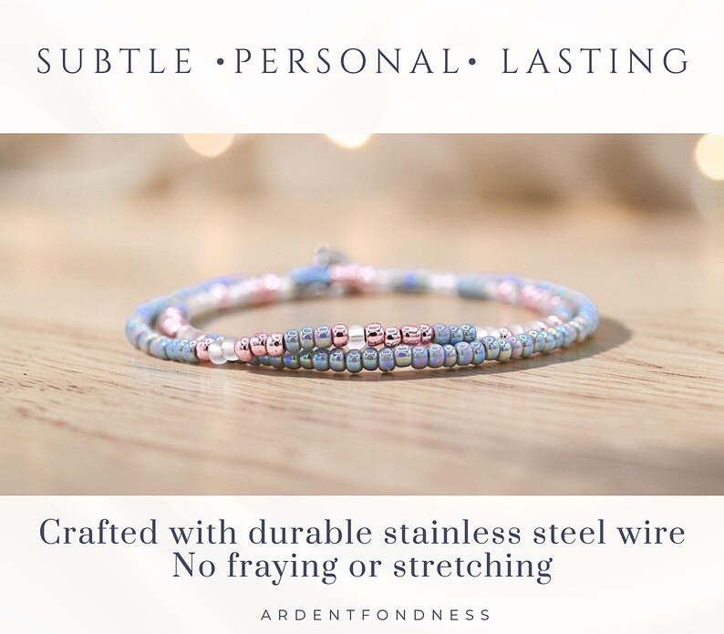 May include: A delicate beaded bracelet in shades of blue, pink, and rose gold. The bracelet is made with small, round beads strung on durable stainless steel wire. The text reads "SUBTLE &bull; PERSONAL &bull; LASTING" and "Crafted with durable stainless steel wire No fraying or stretching".