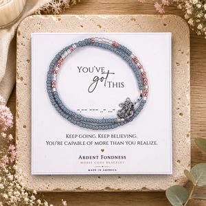 May include: A beaded bracelet with blue, clear, and metallic pink beads and a silver elephant charm on a white card. The card features the text "YOU'VE got THIS", Morse code dots and dashes, and the phrase "KEEP GOING. KEEP BELIEVING."