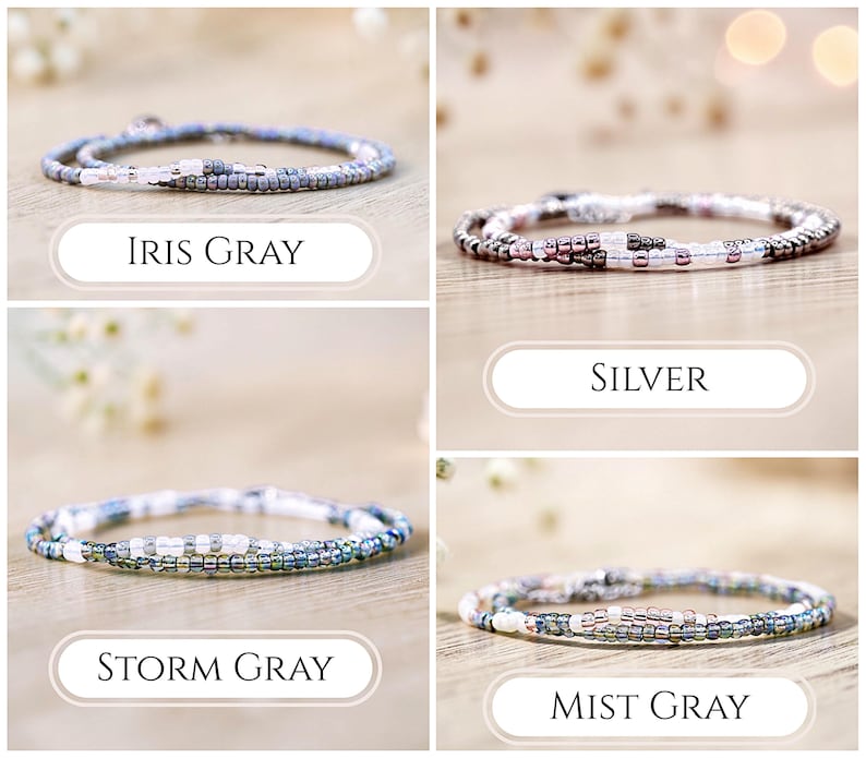 K&ouml;nnte beinhalten: Vier zarte Perlenarmb&auml;nder aus kleinen, runden Glasperlen in verschiedenen Farbpaletten. Die Armb&auml;nder sind mit Iris Gray, Silver, Storm Gray und Mist Gray beschriftet und zeigen Kombinationen aus wei&szlig;en, grauen, metallischen und bl&auml;ulichen Perlen.