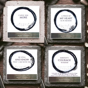 May include: Four black beaded Morse code bracelets displayed on white cards. Each card features a unique phrase: I LOVE YOU MORE, A PIECE OF MY HEART IS IN HEAVEN, BE STILL AND KNOW THAT I AM WITH YOU, and SERENITY COURAGE WISDOM. Each bracelet has a metal clasp.