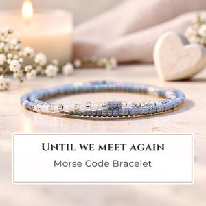 May include: A delicate beaded bracelet featuring a pattern of blue, silver, and clear glass beads arranged in a Morse code sequence. The text "UNTIL WE MEET AGAIN" and "Morse Code Bracelet" is printed in black on a white rectangular label.