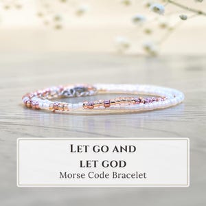 May include: A delicate beaded bracelet featuring a pattern of small white and metallic rose gold beads arranged in a sequence. The bracelet is presented with text that reads: LET GO AND LET GOD Morse Code Bracelet, indicating the design.