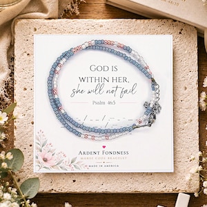 May include: A beaded bracelet with blue, clear, and metallic rose gold beads on a display card. The card features the text "GOD IS WITHIN HER, she will not fail, Psalm 46:5", Morse code dots and dashes, and the brand name "ARDENT FONDNESS".