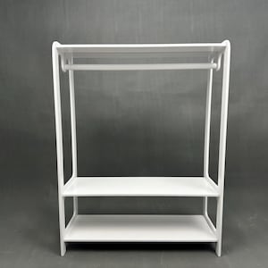 May include: A white wooden clothing rack with two shelves and a hanging rod. The rack has a minimalist design with clean lines and a simple, functional aesthetic. The shelves are ideal for storing shoes or folded clothes.