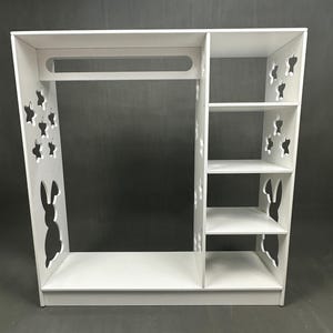 May include: White wooden children's wardrobe with a hanging rod and shelves. The wardrobe features cut-out star and bunny rabbit designs on the sides. The wardrobe is designed for a child's room.