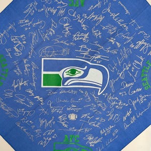 May include: Blue bandana featuring the Seattle Seahawks logo and numerous signatures. The bandana has green and white accents, with text that reads "AFC" and "Western Division Champions 1988".