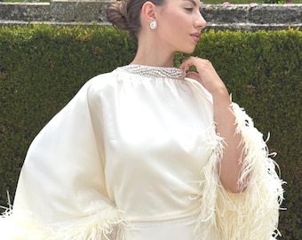 Vestido de novia con plumas en color blanco roto.