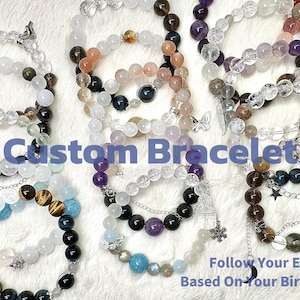 May include: An assortment of custom bracelets made with various gemstones and beads. The bracelets feature a variety of colors, including black, white, brown, purple, and blue. Text on the image reads "Custom Bracelet" and "Follow Your Energy Based On Your Birthday."