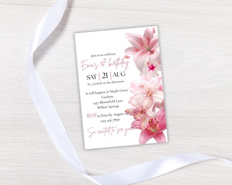 May include: A white invitation card with pink floral accents and text. The invitation reads "Ema's 1st birthday" with the date, time, and location. A white ribbon is draped across the top and bottom of the card.