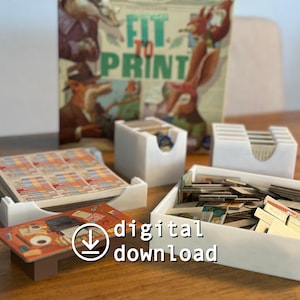 Könnte beinhalten: Brettspiel "Fit to Print" mit Spielkomponenten in weißen Behältern. Das Bild zeigt Spielkarten, Spielsteine und ein Spielbrett. Die Worte "digital download" sind ebenfalls sichtbar.