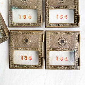 Buzón vintage de vidrio y latón con puerta numerada, con gráficos estampados, metal industrial recuperado, 134, 144, 154 y 164