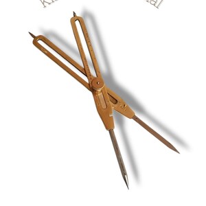May include: A vintage brass proportional divider with sharp points, used for scaling measurements. The tool is marked with the text "King international" and "100% Quality". The divider is set against a white background.