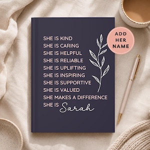 May include: A dark purple hardcover journal featuring white text that reads: SHE IS KIND, SHE IS CARING, SHE IS HELPFUL, SHE IS RELIABLE, SHE IS UPLIFTING, SHE IS INSPIRING, SHE IS SUPPORTIVE, SHE IS VALUED, SHE MAKES A DIFFERENCE, SHE IS Sarah, and a leaf graphic.