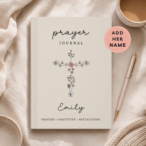 May include: A beige prayer journal featuring the text prayer JOURNAL, the name Emily, and the words PRAYERS GRATITUDE REFLECTIONS. A cross shape made of small black and pink floral illustrations is centered on the cover. A pink circle with the text ADD HER NAME is visible in the upper right corner.
