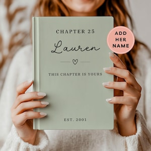 May include: A sage green hardcover book featuring black text that reads CHAPTER 25, Lauren, a small heart icon, THIS CHAPTER IS YOURS, and EST. 2001. A circular pink sticker on the upper right corner contains the text ADD HER NAME in black.