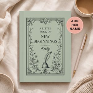 May include: A sage green hardcover book with a black decorative border featuring floral motifs. The text reads A LITTLE BOOK OF NEW BEGINNINGS and the name Emily, accompanied by a black inkwell and quill illustration centered on the front cover.